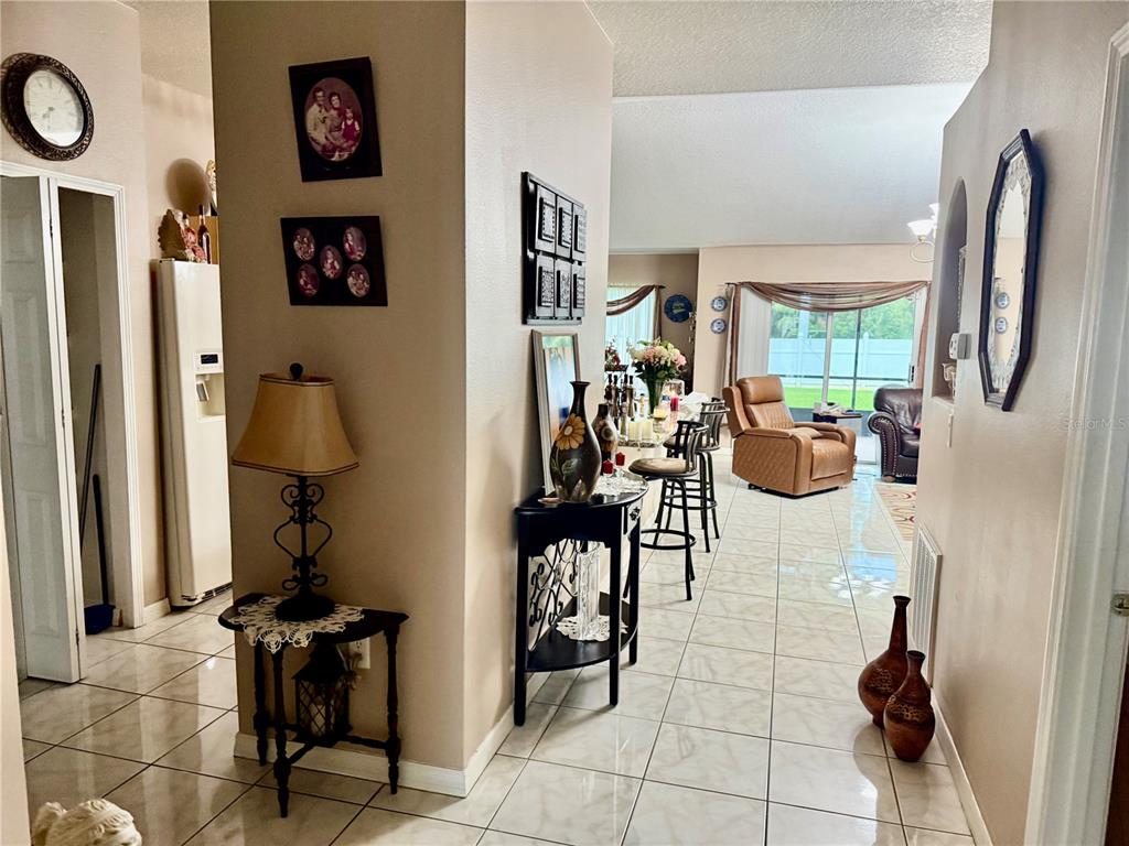 A tiled hallway leads into an open living area with a kitchen island and seating — 68 RIVERVIEW DRIVE, PALM COAST, FL