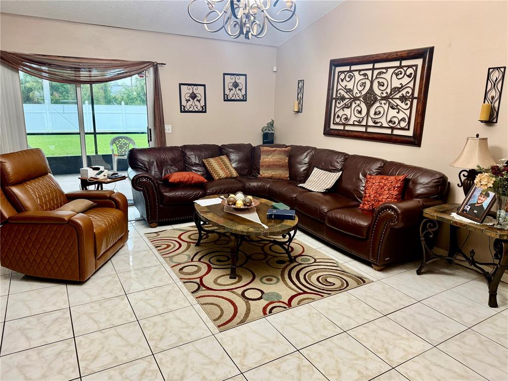 A living room features a large brown leather sectional, a recliner, and a patterned area rug — 68 RIVERVIEW DRIVE, PALM COAST, FL