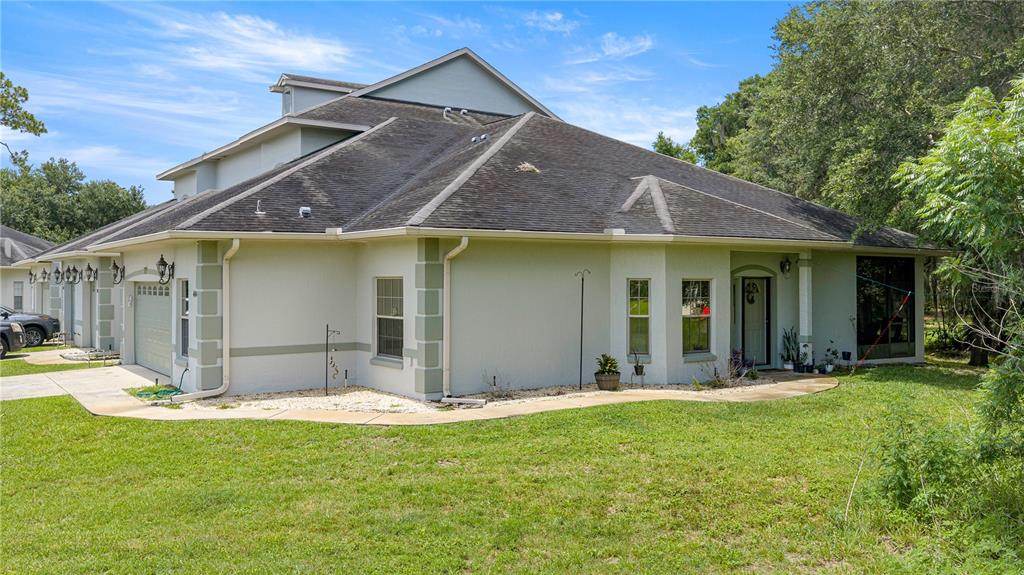 An exterior view of a light-colored stucco house with a dark shingled roof and lawn — 3415 W ANTHONY ROAD UNIT 404, OCALA, FL