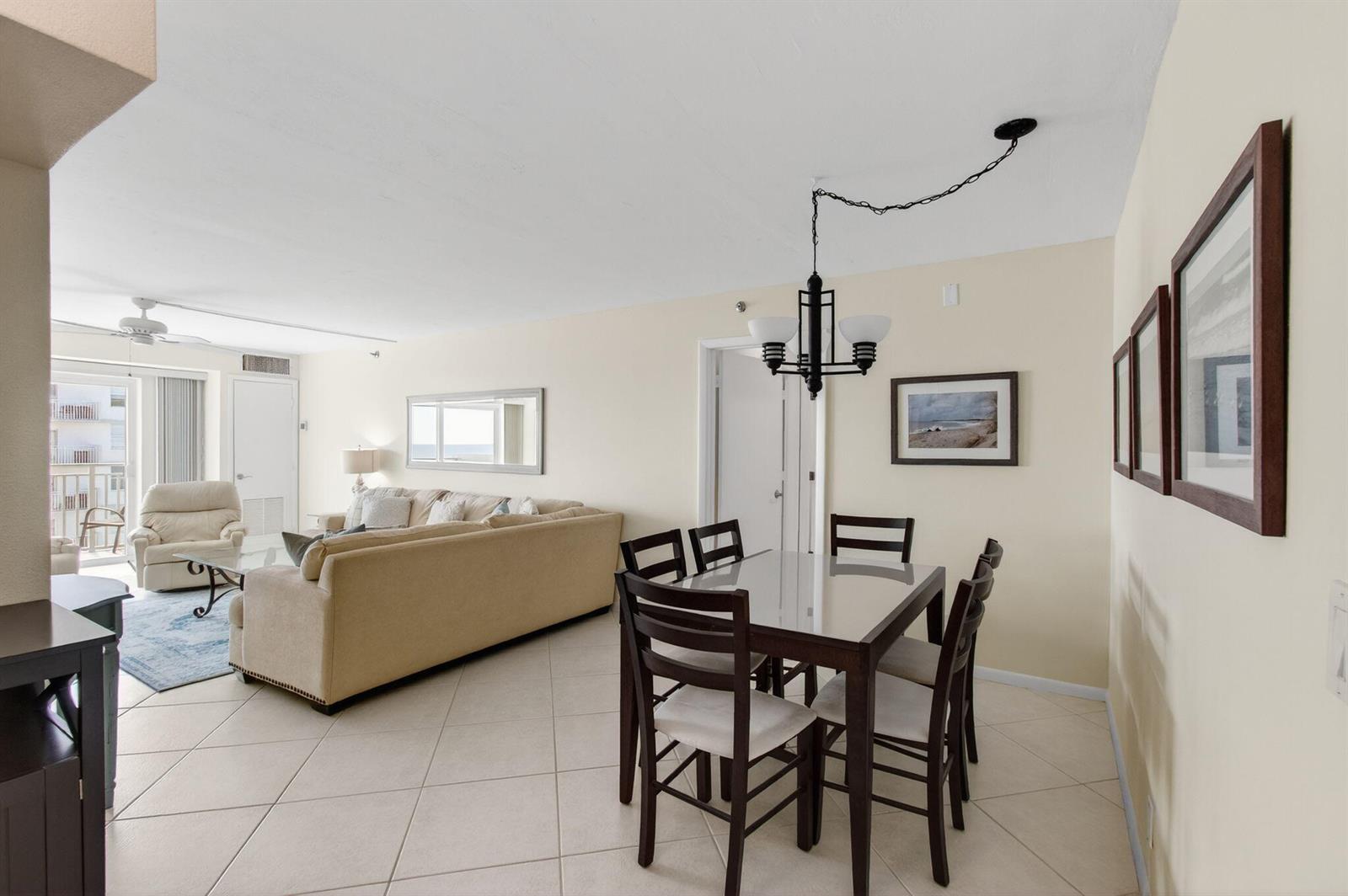 A dining area with a glass-top table sits adjacent to a living room with tile flooring — 4505 S Ocean Boulevard # 905, Highland Beach FL 33487, HIGHLAND BEACH, FL