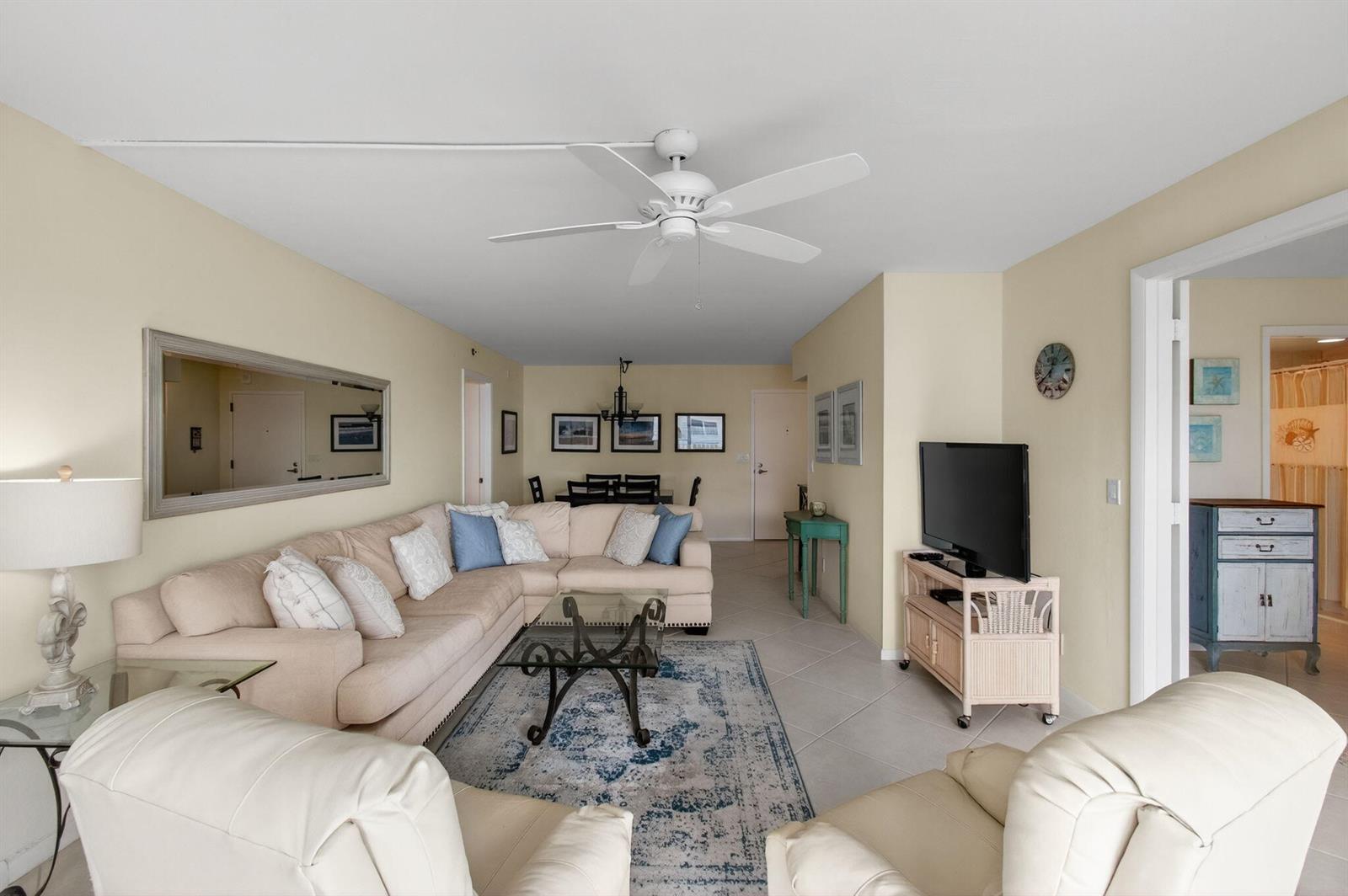 A living room with a sectional sofa, television, and dining area on a tile floor — 4505 S Ocean Boulevard # 905, Highland Beach FL 33487, HIGHLAND BEACH, FL