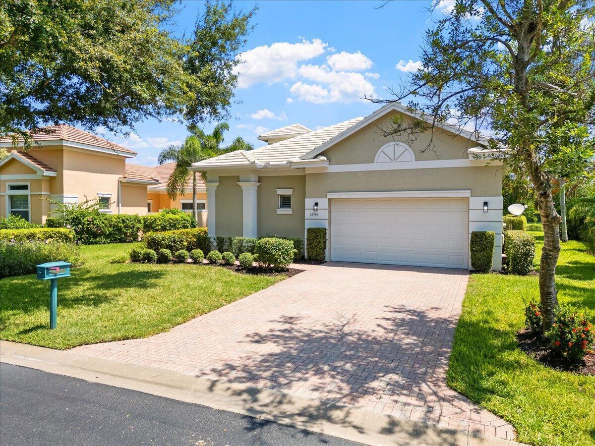 A single-story house with a beige exterior, a two-car garage, and a paved driveway — 1254 River Reach Drive, Vero Beach FL 32967, VERO BEACH, FL