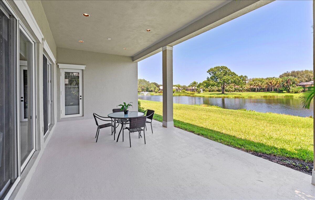 A covered patio with a dining set overlooks a grassy lawn and a pond — 1254 River Reach Drive, Vero Beach FL 32967, VERO BEACH, FL
