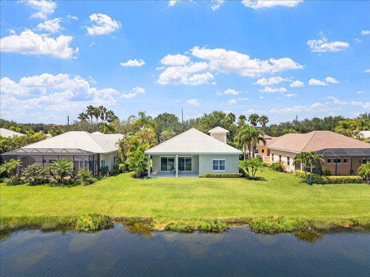 An aerial view of a light green house with a tiled roof beside a pond — 1254 River Reach Drive, Vero Beach FL 32967, VERO BEACH, FL