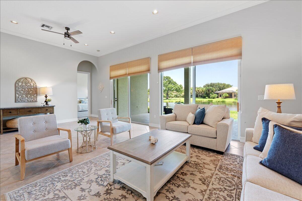 A living room with light tile floors, neutral furniture, and sliding doors overlooking a lake — 1254 River Reach Drive, Vero Beach FL 32967, VERO BEACH, FL