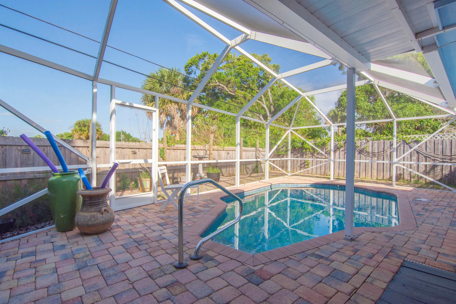 A screened-in patio features a small swimming pool with brick pavers and a wooden fence — 1545 Highland Avenue, Vero Beach FL 32960, VERO BEACH, FL