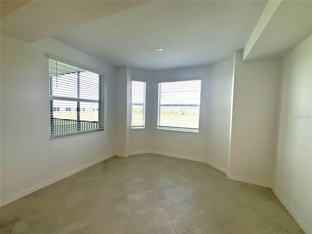 An empty room with white walls, tile flooring, and a bay window with blinds — 17625 OPAL SAND DRIVE UNIT 202, VENICE, FL