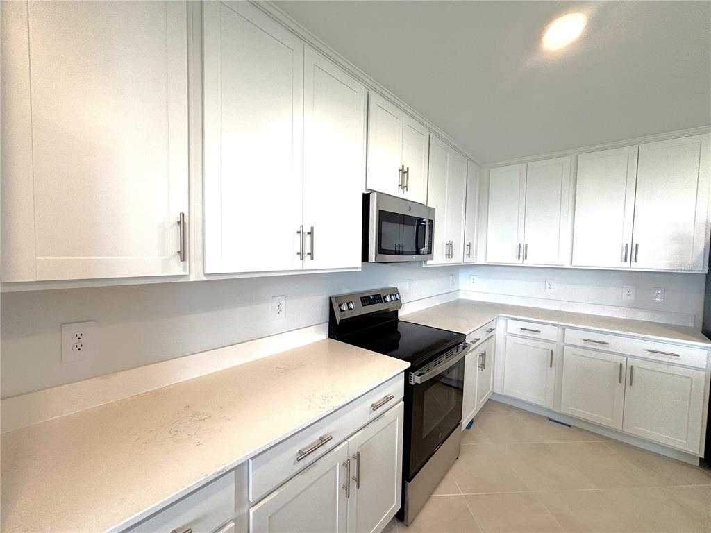 A kitchen features white cabinets, stainless steel appliances, and light-colored countertops — 17625 OPAL SAND DRIVE UNIT 202, VENICE, FL