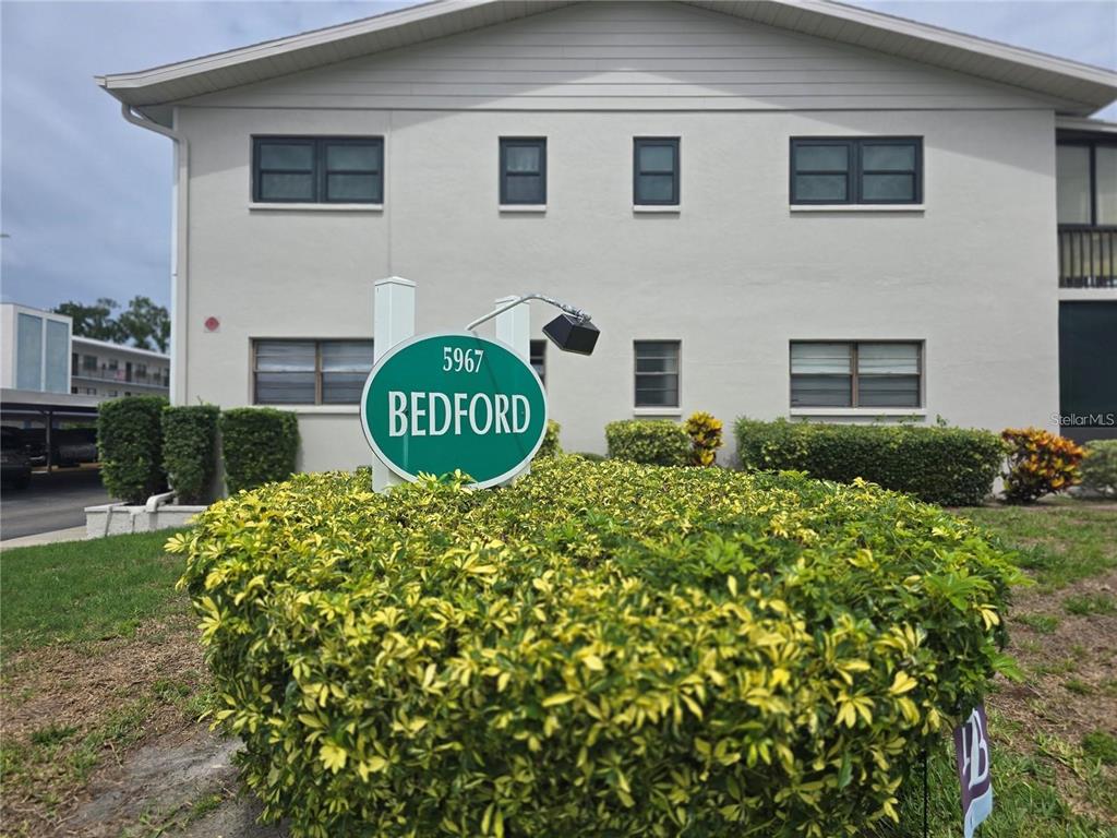 A two-story apartment building exterior features a green sign labeled Bedford in front of landscaping — 5967 TERRACE PARK DRIVE N UNIT 206, ST PETERSBURG, FL