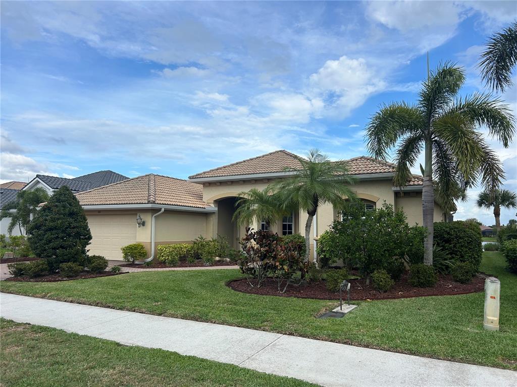 A single-story house with a tan stucco exterior, a tile roof, and a palm tree — 110 CANELETTO WAY, NORTH VENICE, FL