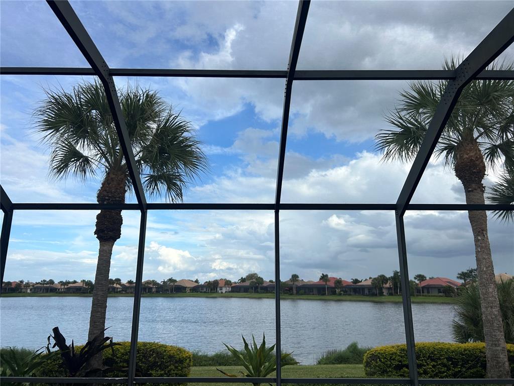 A view of a lake and neighborhood houses seen through a screened-in patio enclosure — 110 CANELETTO WAY, NORTH VENICE, FL