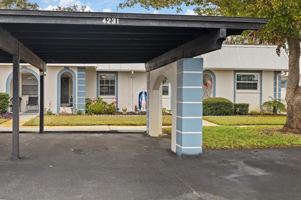 A carport with a black roof and blue pillars stands in front of a house — 4231 RICHMERE DRIVE UNIT 3D, NEW PORT RICHEY, FL
