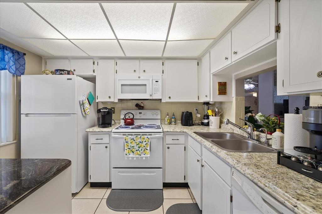 A kitchen features white cabinets, granite countertops, a white refrigerator, and a drop ceiling — 4231 RICHMERE DRIVE UNIT 3D, NEW PORT RICHEY, FL