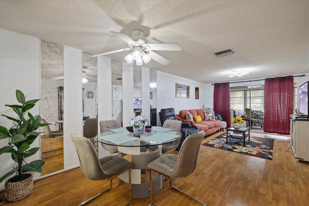 A dining area with a glass table and mirrored wall opens into a living room — 4231 RICHMERE DRIVE UNIT 3D, NEW PORT RICHEY, FL