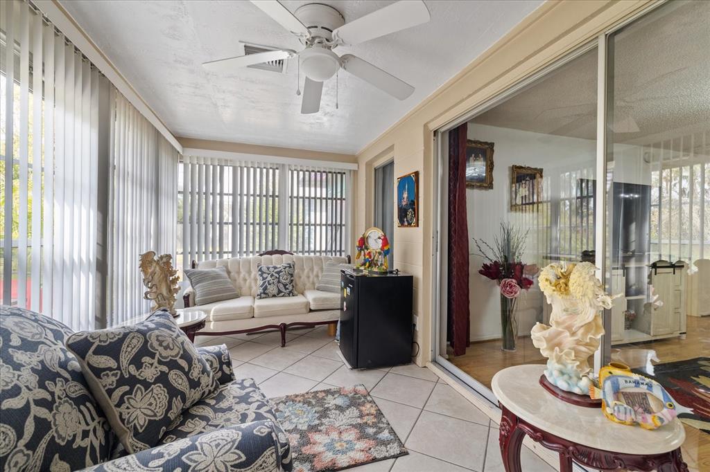 A sunroom with tile floors, a ceiling fan, a sofa, and a glass sliding door — 4231 RICHMERE DRIVE UNIT 3D, NEW PORT RICHEY, FL