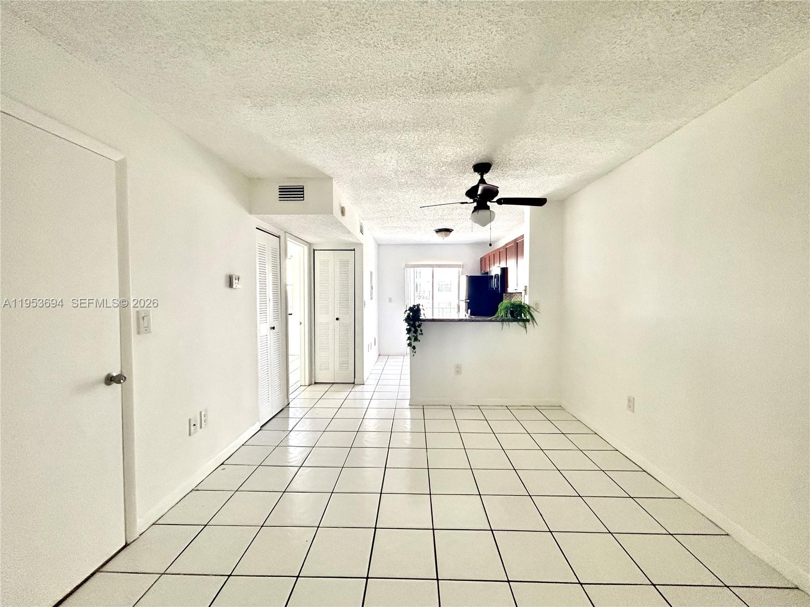 A bright, tiled living area leads to an open kitchen with a breakfast bar — 2575 SW 27th Ave # 509, Miami FL 33133, MIAMI, FL