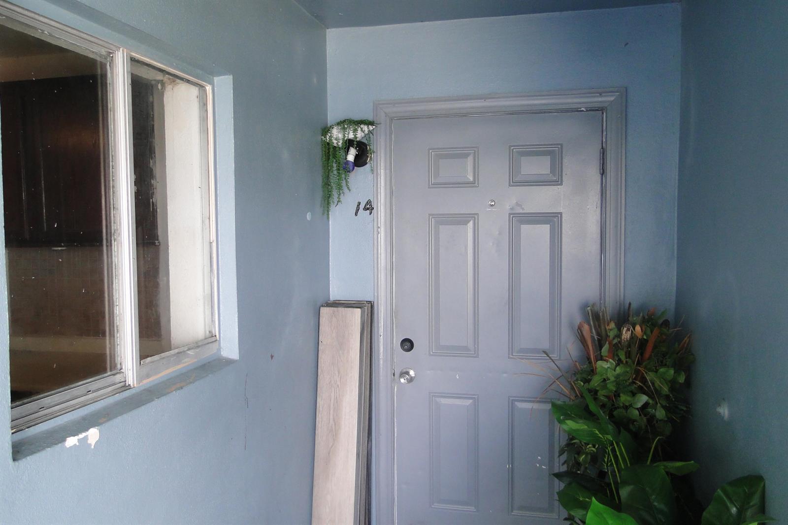 A gray front door with the number 14 is located next to a window and plants — 1829 N A Street # 14, FL 33460, FL