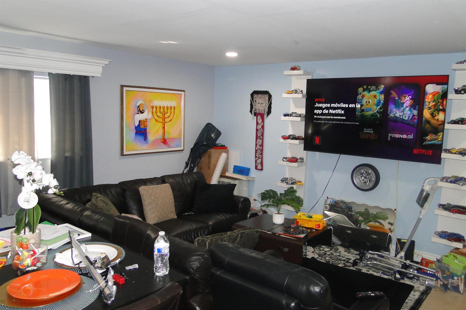 A living room features a black leather sofa, a wall-mounted television, and shelves displaying cars — 1829 N A Street # 14, FL 33460, FL