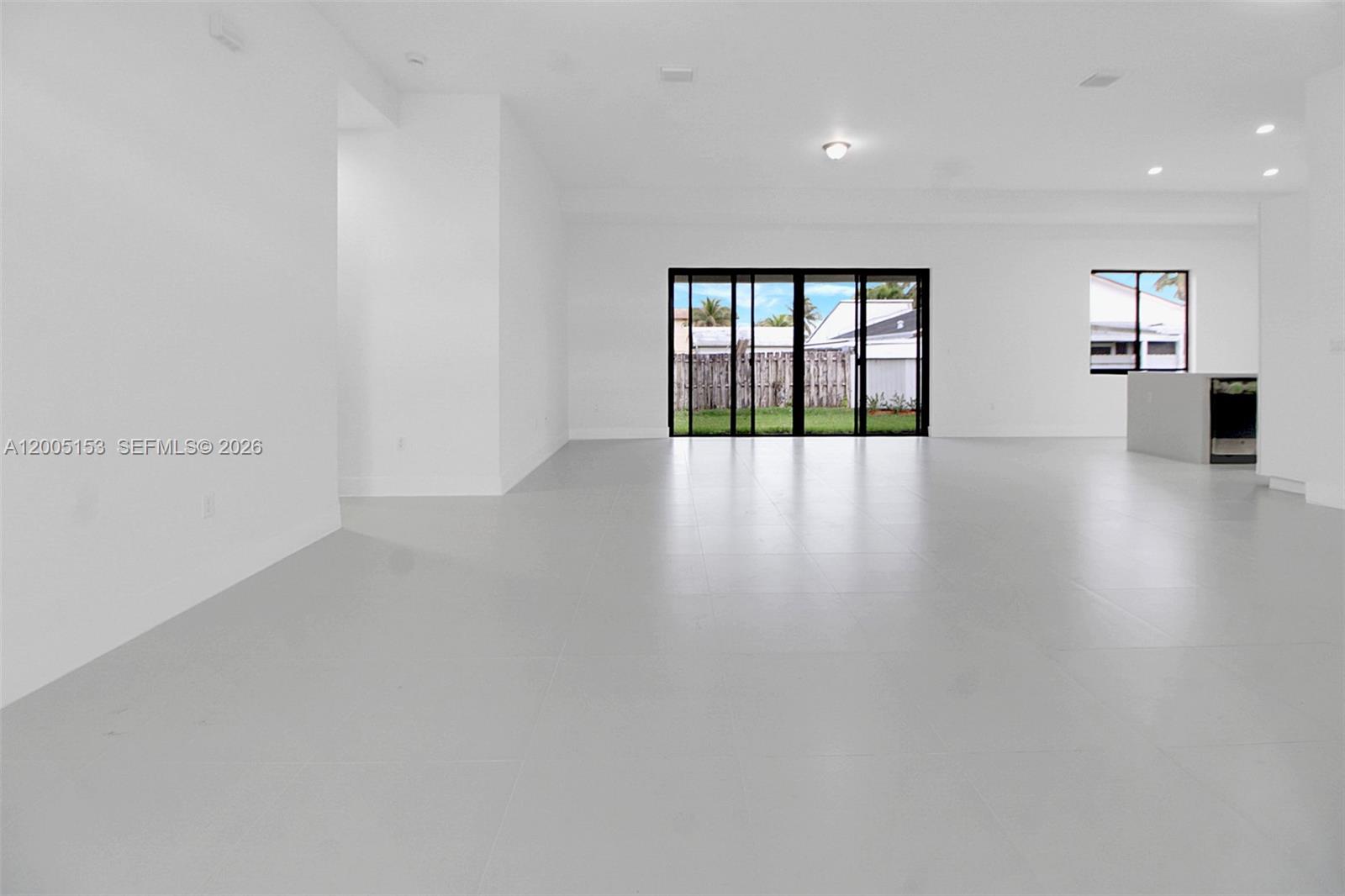 This interior view shows a spacious, white-walled living area with large tile flooring and sliding doors — 20833 SW 96th Ct, Cutler Bay FL 33189, CUTLER BAY, FL
