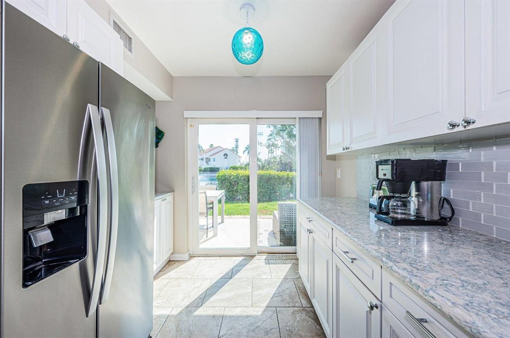 A kitchen with white cabinets, granite countertops, stainless steel appliances, and a sliding glass door — 6107 MIRADA CIRCLE, ST PETERSBURG, FL