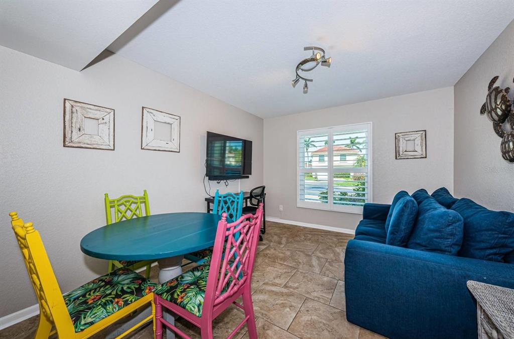 A room with a blue sofa, a colorful dining set, and a wall-mounted television — 6107 MIRADA CIRCLE, ST PETERSBURG, FL