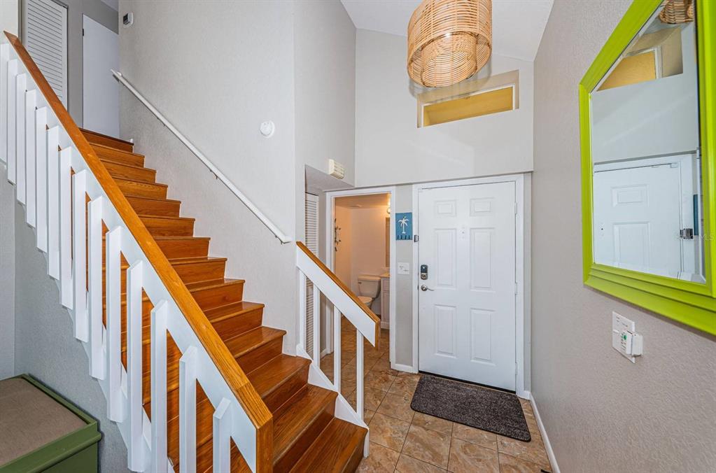 An entryway features a wooden staircase, a white front door, and a lime green mirror — 6107 MIRADA CIRCLE, ST PETERSBURG, FL