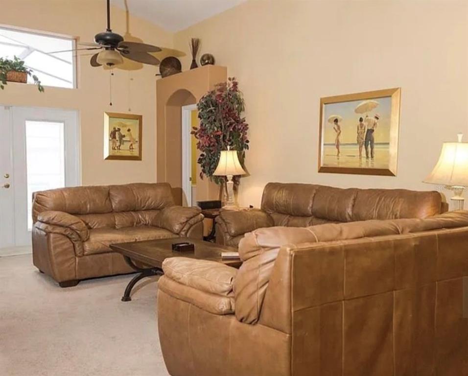 A living room features brown leather sofas, a coffee table, and wall art — 2697 AUTUMN CREEK CIRCLE, KISSIMMEE, FL