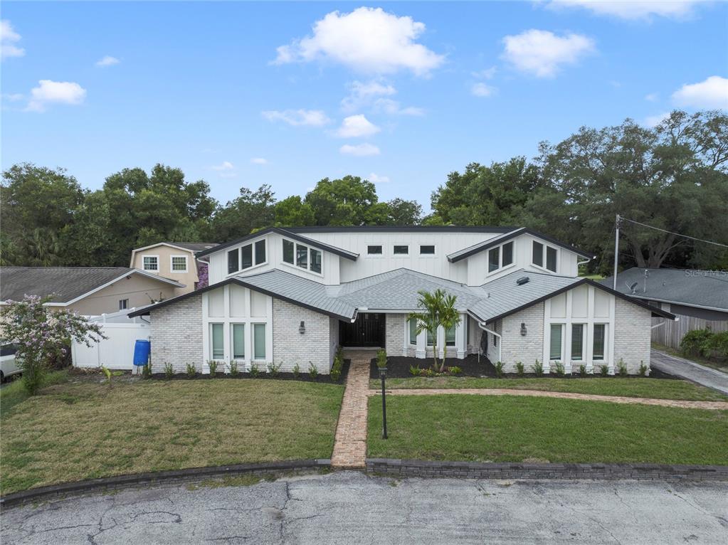 A single-story house with a white brick facade, dark trim, and a brick walkway — 1048 CRYSTAL BOWL CIRCLE, CASSELBERRY, FL