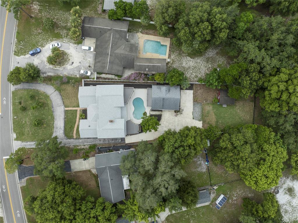 An aerial view shows three houses with swimming pools and driveways surrounded by wooded areas — 1048 CRYSTAL BOWL CIRCLE, CASSELBERRY, FL
