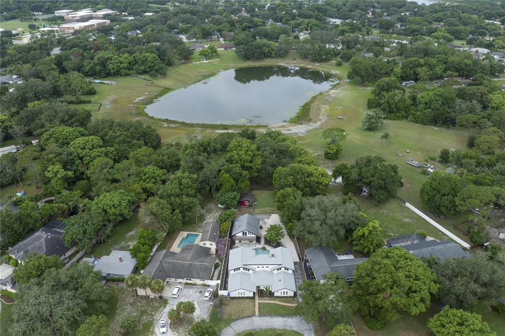 An aerial view shows a residential property with a pool situated near a large pond — 1048 CRYSTAL BOWL CIRCLE, CASSELBERRY, FL