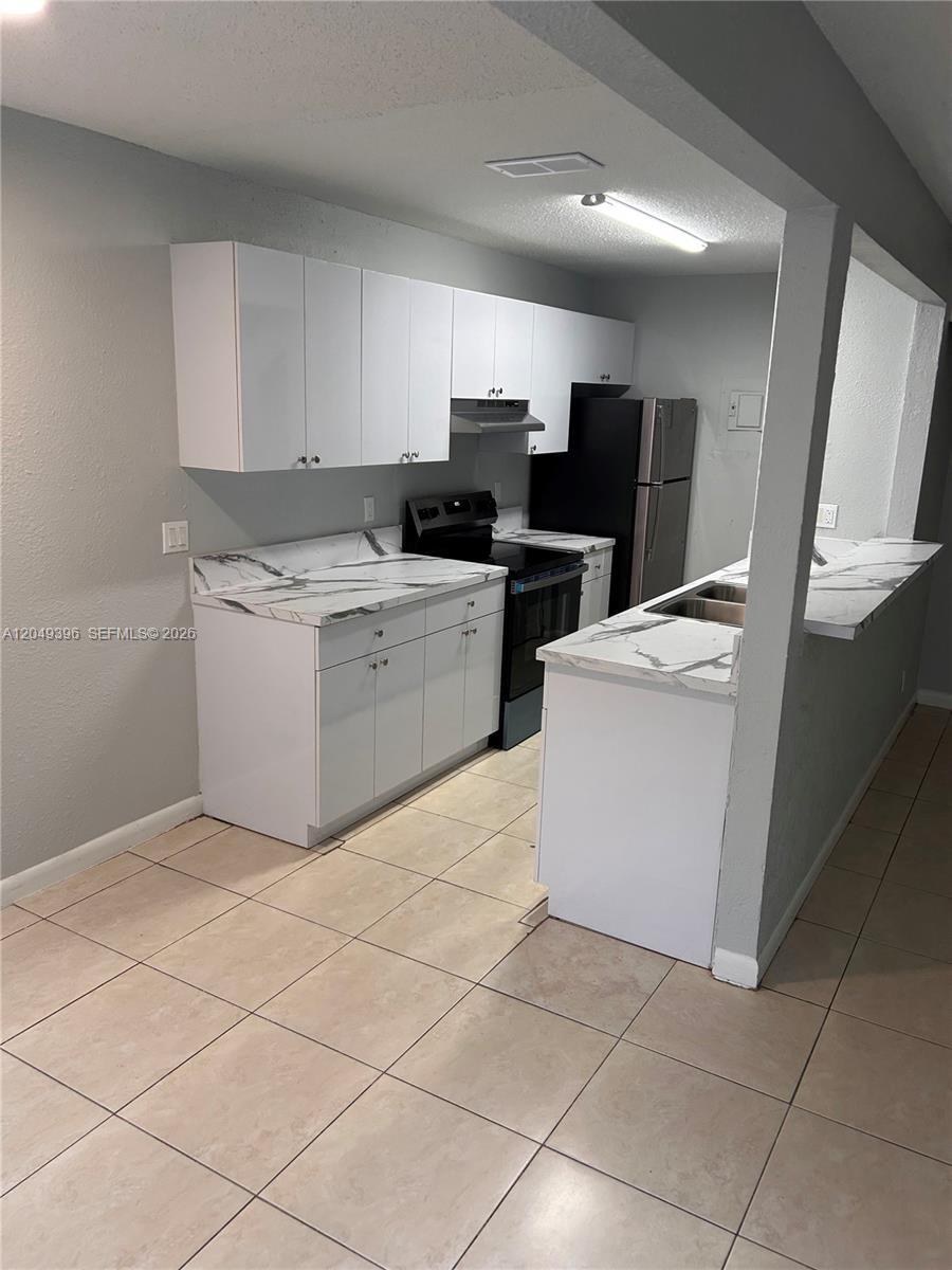 A kitchen features white cabinets, marble-patterned countertops, and tile flooring — 1530 S Congress Ave # 2, Delray Beach FL 33445, DELRAY BEACH, FL