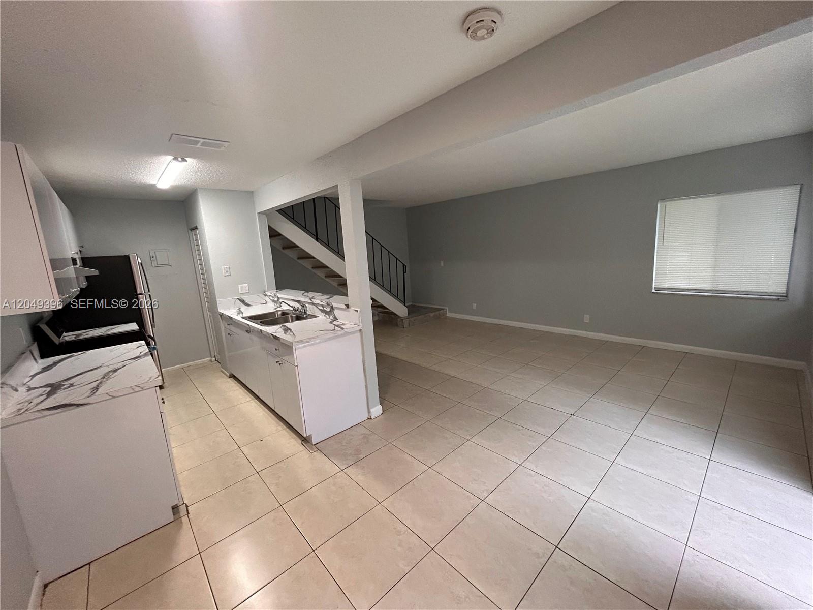A kitchen with white cabinets and marble-look countertops opens into a tiled living area — 1530 S Congress Ave # 2, Delray Beach FL 33445, DELRAY BEACH, FL