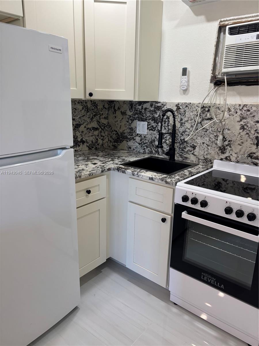 A small kitchen features white cabinets, granite countertops, a black sink, and white appliances — 103365 Overseas Hwy # A, Key Largo FL 33037, KEY LARGO, FL