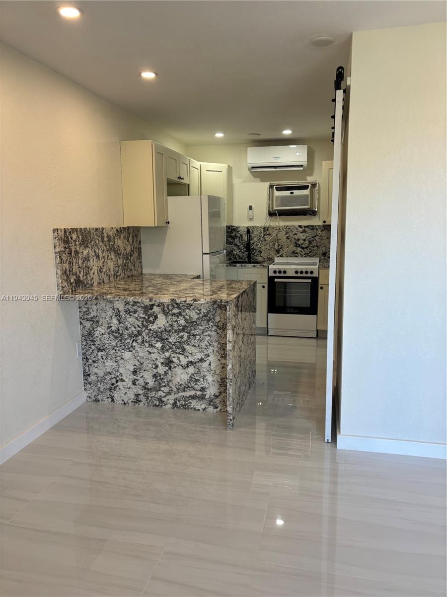 A small kitchen features granite countertops, white cabinets, and a white stove — 103365 Overseas Hwy # A, Key Largo FL 33037, KEY LARGO, FL