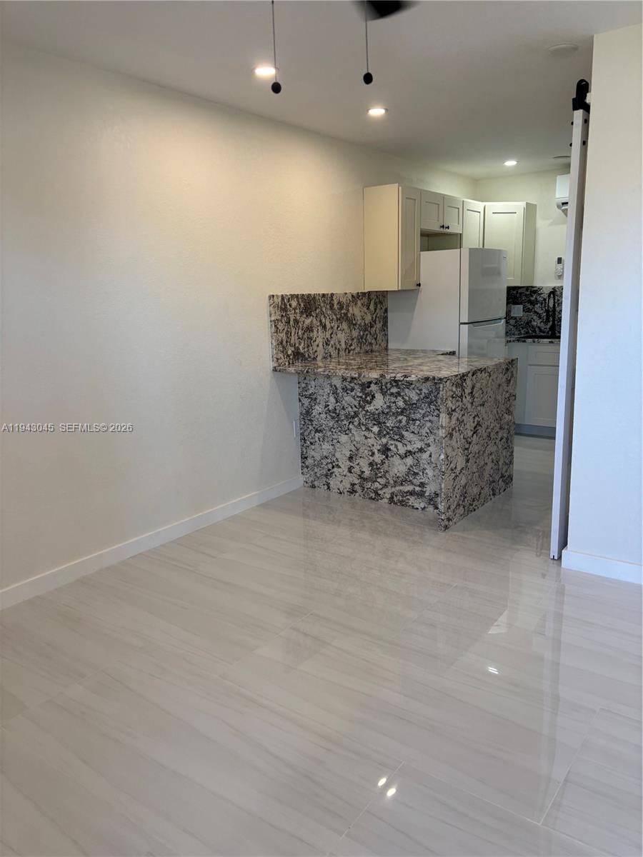 A kitchen features a granite-topped peninsula, white cabinets, and light-colored tile flooring — 103365 Overseas Hwy # A, Key Largo FL 33037, KEY LARGO, FL
