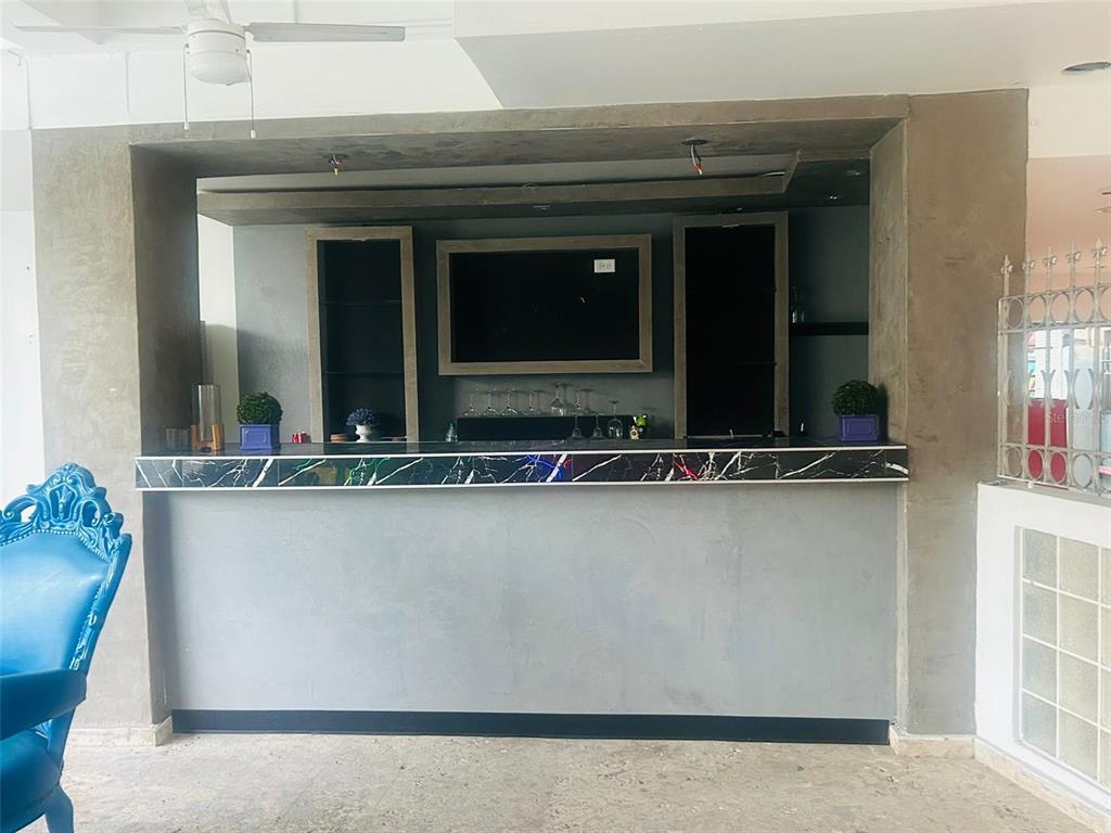 A home bar features a gray concrete-style counter, a black marble-patterned top, and built-in shelving — 75 CALLE CRISTINA, PONCE, PR