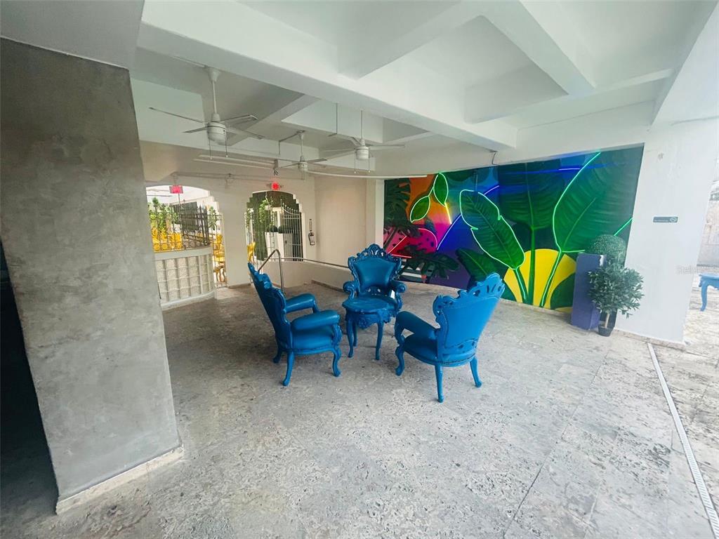 A covered outdoor patio features three blue ornate chairs and a vibrant neon-lit mural — 75 CALLE CRISTINA, PONCE, PR