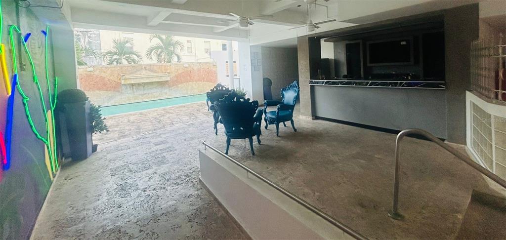 An outdoor patio area features a bar, pool, and several blue chairs on stone flooring — 75 CALLE CRISTINA, PONCE, PR