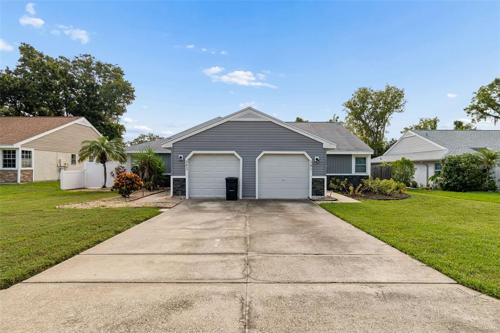 A duplex house with two garage doors and a concrete driveway under a blue sky — 341 HIBISCUS DRIVE, PALM HARBOR, FL