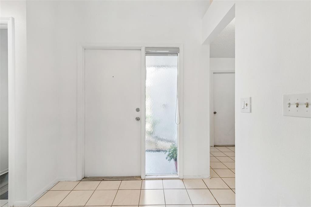 An entryway features white walls, light-colored floor tiles, a front door, and a side window — 341 HIBISCUS DRIVE, PALM HARBOR, FL