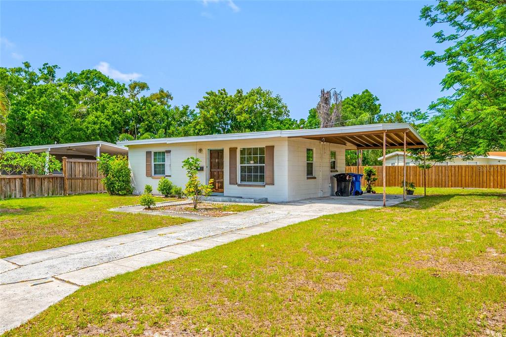 A single-story house with a carport, concrete driveway, and a fenced yard under a blue sky — 289 43RD TERRACE SE, ST PETERSBURG, FL
