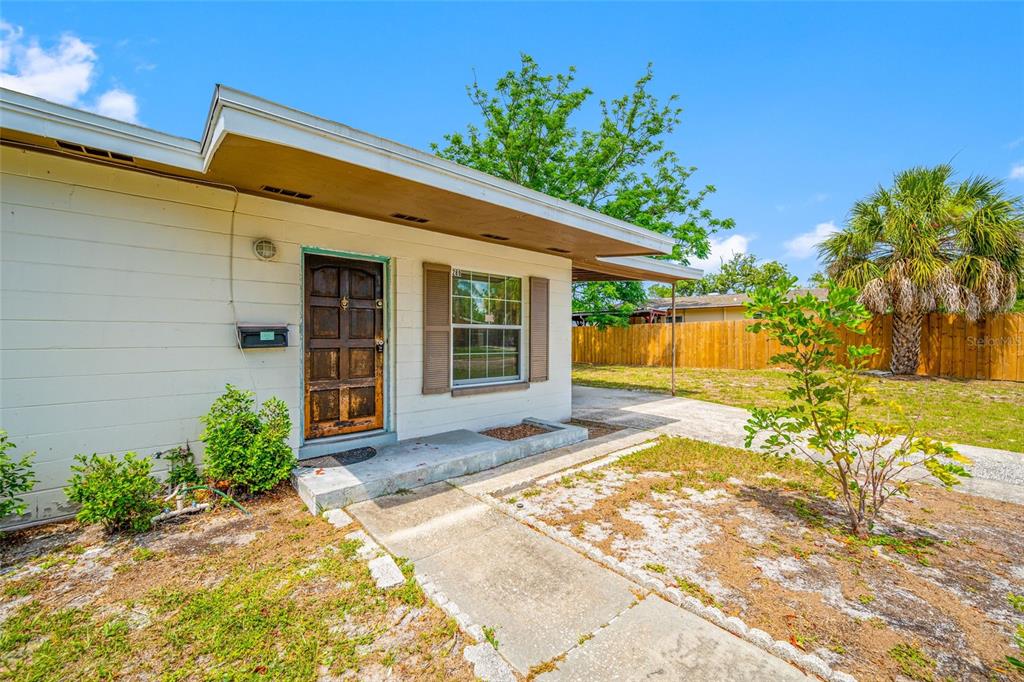 A single-story house exterior features a wooden front door, a window with shutters, and landscaping — 289 43RD TERRACE SE, ST PETERSBURG, FL
