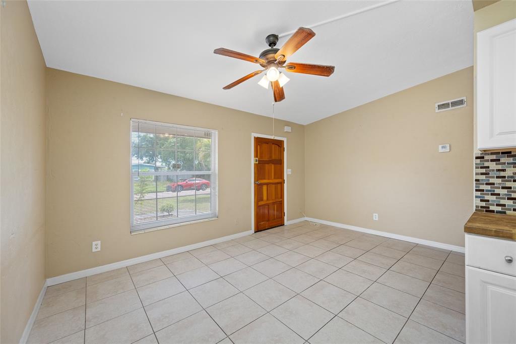 A dining area features beige walls, light tile flooring, a ceiling fan, and a wooden door — 289 43RD TERRACE SE, ST PETERSBURG, FL