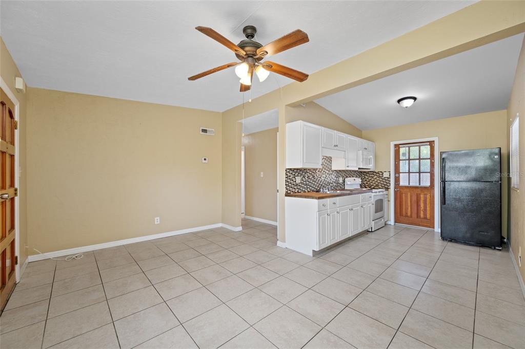 A kitchen and dining area with tile floors, white cabinets, and a ceiling fan — 289 43RD TERRACE SE, ST PETERSBURG, FL