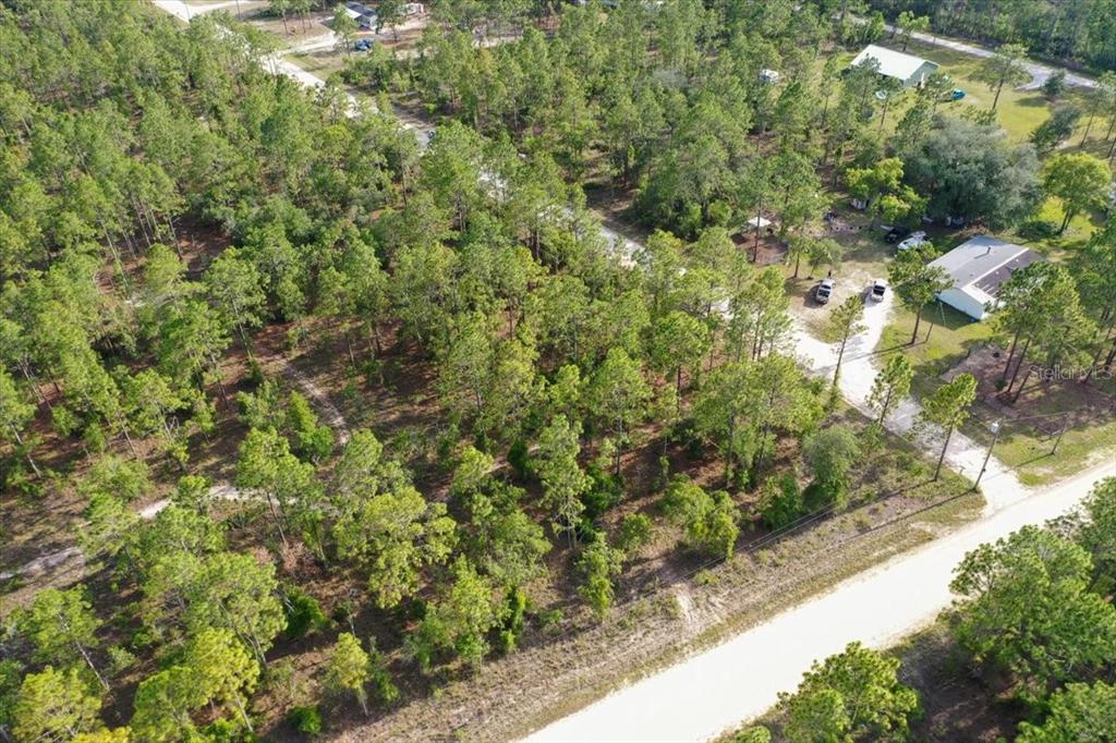 An aerial view shows a wooded lot adjacent to a dirt road and nearby houses — 0000 NE 131 LOT 10 TERRACE, WILLISTON, FL