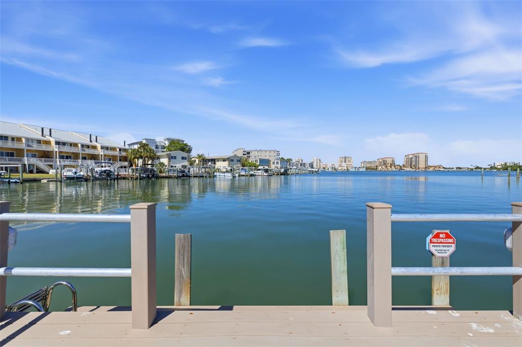 A view from a wooden dock looking out over a calm bay toward waterfront buildings — 400 LARBOARD WAY UNIT 105, CLEARWATER BEACH, FL