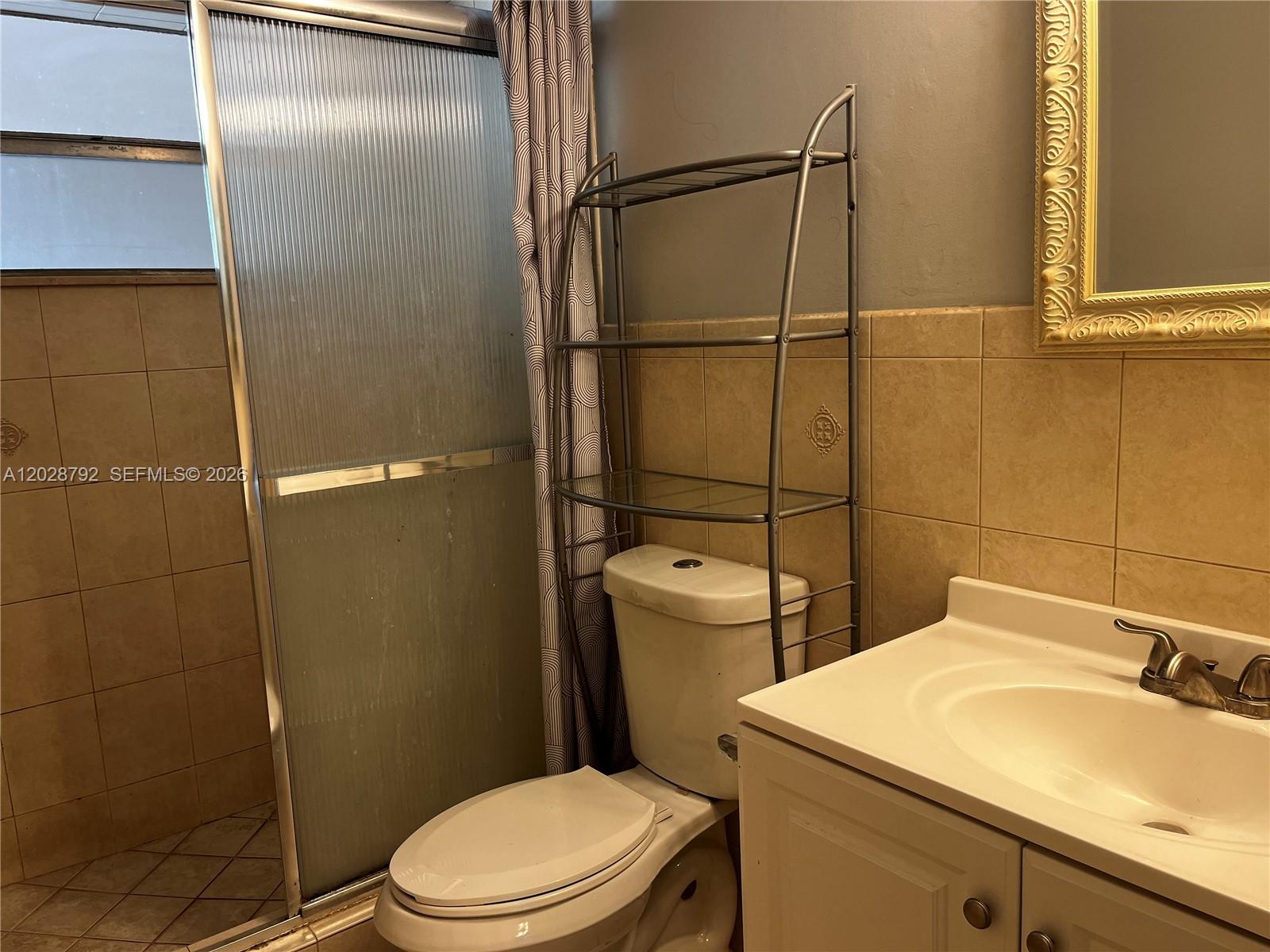 A bathroom features a vanity, a toilet with a metal storage rack, and a shower — 7000 Nova Dr # 103E, Davie FL 33317, DAVIE, FL