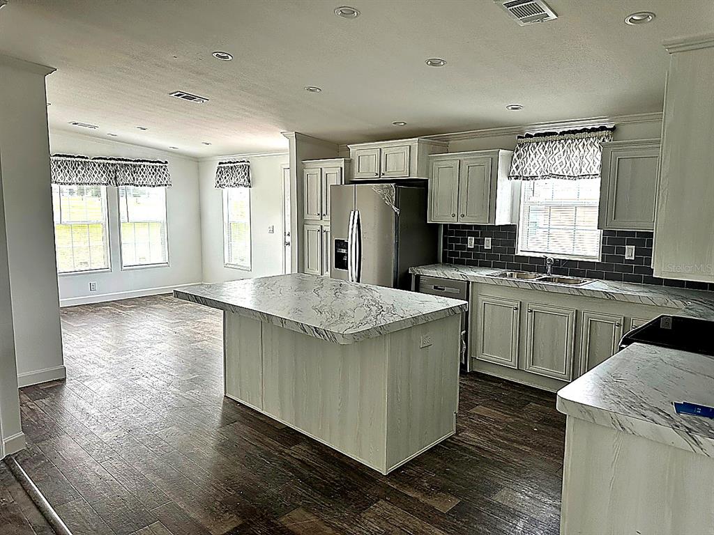 A kitchen features a marble-topped island, light-colored cabinetry, and dark tile backsplash — 3496 GREENBLUFF ROAD UNIT 1118, ZELLWOOD, FL