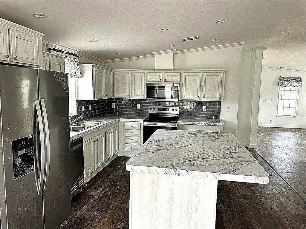 A kitchen features white cabinets, a marble-patterned island, stainless steel appliances, and dark tile backsplash — 3496 GREENBLUFF ROAD UNIT 1118, ZELLWOOD, FL