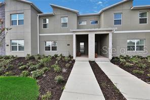 A two-story townhouse exterior with a concrete walkway leading to two front entrances — 392 OCEAN COURSE AVENUE, CHAMPIONS GATE, FL